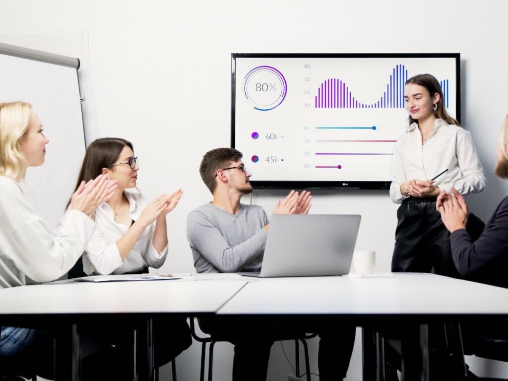 A group of professionals in a meeting room applauding, showcasing teamwork and positive engagement during a discussion.