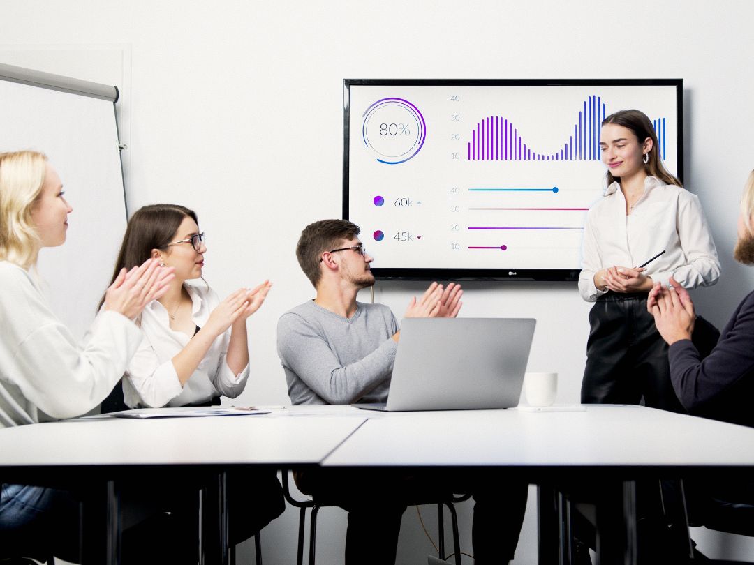 A group of professionals in a meeting room applauding, showcasing teamwork and positive engagement during a discussion.