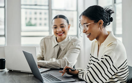 two woman looking at their laptop