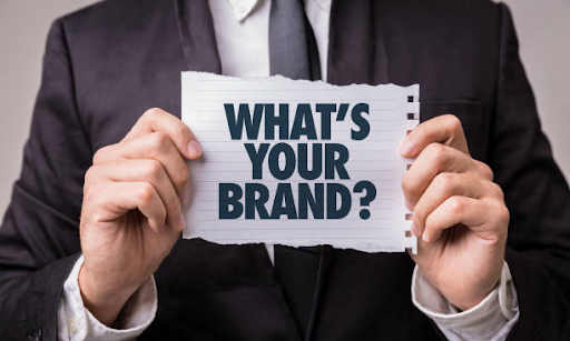 A man holding a paper with what's your brand sign
