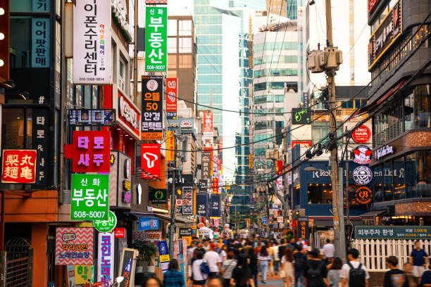 A crowded urban street scene with many people walking and interacting in a lively atmosphere.