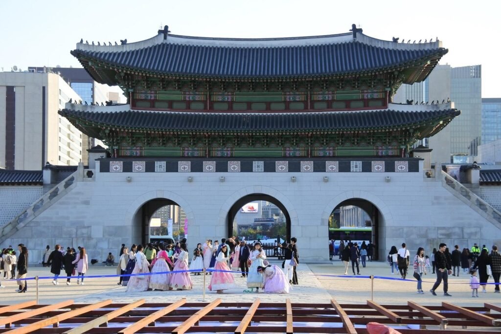 International visitors wearing colourful hanbok in front of Gwanghwamun Gate at Gyeongbokgung Palace in Seoul.