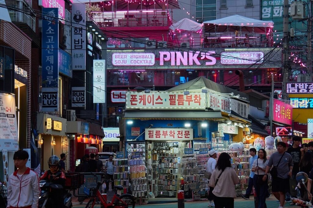 Busy Hongdae street in Seoul with neon signs, shops and pedestrians during the evening.